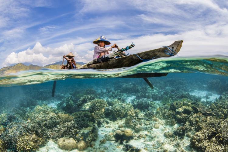 The Ocean: Life & Livelihoods Category - Winner: Two local Indonesian fishermen paddle in a traditional canoe along a shallow coral reef looking for a good place to put down their lines. These fishermen are practicing handline fishing, a type of sustainable fishing without poles or nets. Location: Adonara Island, Flores, Indonesia. Photo by Renee Capozzola, USA.